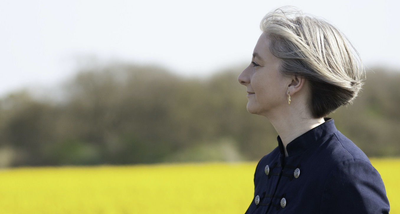 Cornelia Raubal in profile, looking ahead across a field of yellow rapeseed